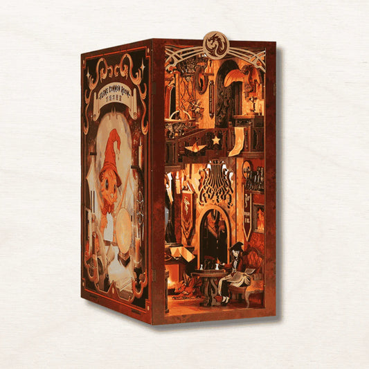 Flame Common Room book nook kit fully assembled and lit between two books, showing a two-floor wizarding common room with glowing LED fireplace and dragon crest