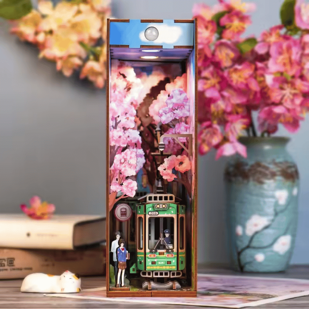 Book nook shaped like a traditional Japanese train, featuring a green color scheme and a cherry blossom tree.