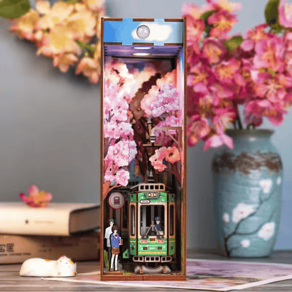 Book nook shaped like a traditional Japanese train, featuring a green color scheme and a cherry blossom tree.