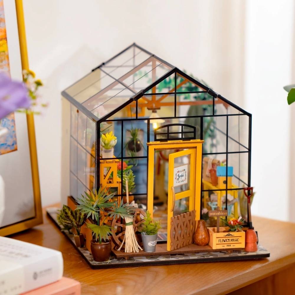 Cathy's Flower House DIY miniature greenhouse assembled — four transparent walls with plants and warm LED glow