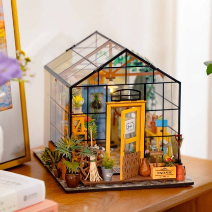 Cathy's Flower House DIY miniature greenhouse assembled — four transparent walls with plants and warm LED glow